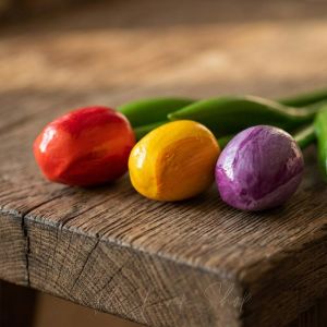 Близък план на автентични дървени лалета в червено, жълто и лилаво, показващ детайлната текстура на боята върху естествено дърво.